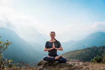Selbstklebende Fototapeten Meditating in lotus position, doing yoga exercises in morning © zulman
