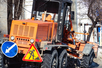 Tractor with snowplow on the street of the city