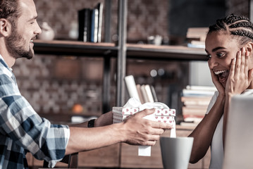 Is this for me. Nice attractive emotional woman looking at the present and holding her cheeks while showing the excitement