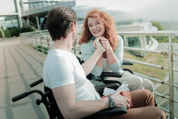 Fototapeta na wymiar In all ears. Positive delighted red haired female person holding hands together while looking forward, feeling happiness