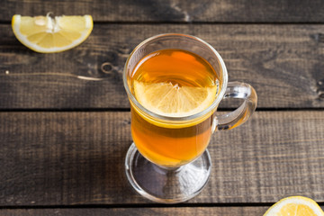 A cup of ginger tea with lemon on a wooden background.