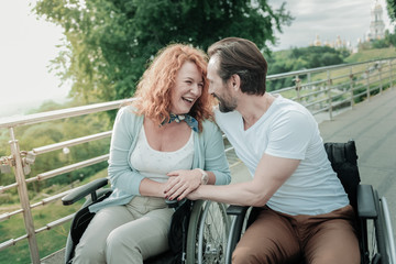 Lets walk. Smiling red haired female laughing at funny joke and embracing her man while sitting on...