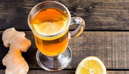 A cup of ginger tea with lemon on a wooden background.