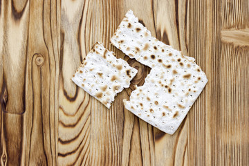 A photo of two pieces of matzah or matza on the wooden table. Matzah for the Jewish Passover holidays. Place for text, copy space. Selective soft focus.