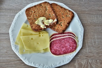 breakfast, on a white plate, salami with cheese, toast with margarine