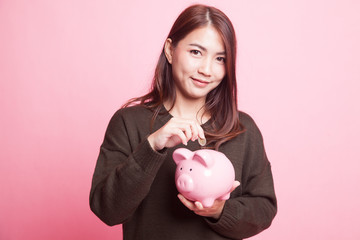 Asian woman with coin and pig coin bank.