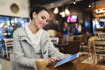Fototapeta premium Attractive young woman using tablet in cafe