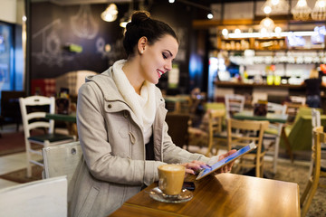Fototapeta na wymiar Attractive young woman using tablet in cafe