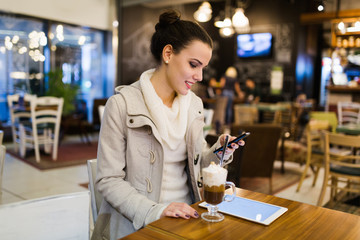 Attractive young woman using tablet in cafe