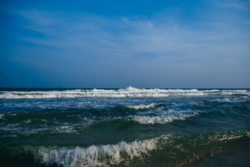 sea with waves on a cloudy day with kitesurfers