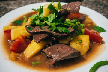 stewed meat with potatoes and vegetables on a plate