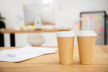 close up view of disposable cups of coffee at workplace with papers in office