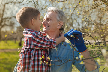 Love you so much. Caring retired man smiling and holding his little grandson while standing in the...