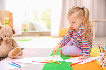 Little cute girl drawing on floor indoors