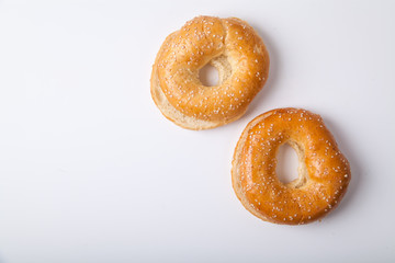 Two fresh baked bagle buns with sesame seeds on white background pre-cut for making sandwiches