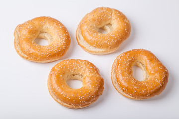 Four fresh baked bagle buns with sesame seeds on white background pre-cut for making sandwiches