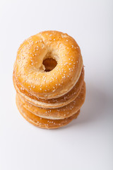 Four fresh baked bagle buns with sesame seeds on white background pre-cut for making sandwiches