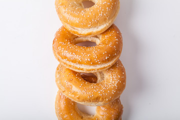 Four fresh baked bagle buns with sesame seeds on white background pre-cut for making sandwiches