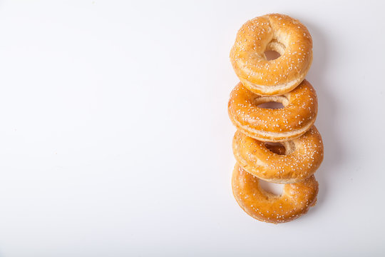Four fresh baked bagle buns with sesame seeds on white background pre-cut for making sandwiches