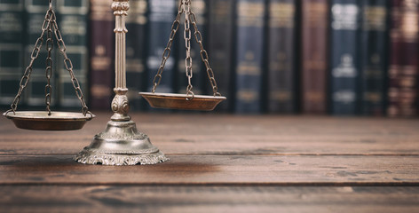 Scales of Justice and Law books on a  wooden background.