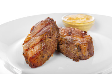 Steak of dark beef, pork, lamb, grilled meat, barbecue, on a plate isolated white background. Mustard, yellow sauce. Juicy fillet, medium, strong roast. For the menu in the restaurant, bar. Side view
