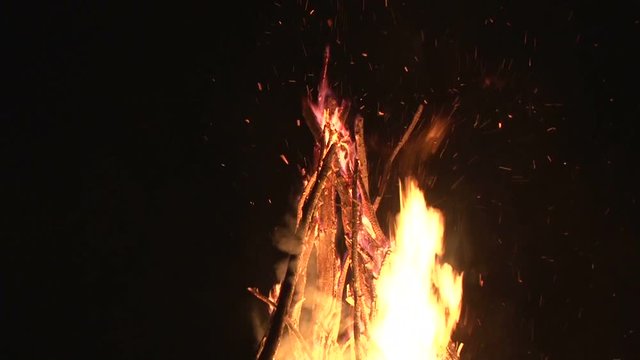 night fire sparks flying in the dark night sky, big night bonfire in a clearing in the forest