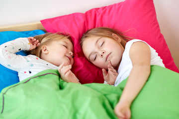 happy little girls sleeping in bed at home