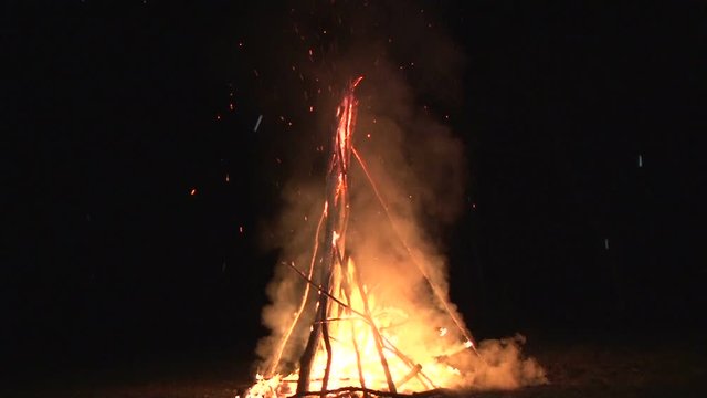 night fire sparks flying in the dark night sky, big night bonfire in a clearing in the forest
