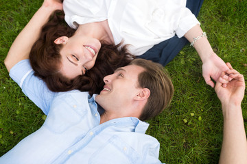 Couple looking at each other while lying down on the grass