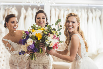 Happy women brides with flowers in wedding salon
