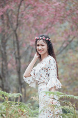 Portrait of attractive Asian teenage girl around the age of 18-25 years amid pink flower garden.