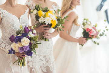 Close-up view of brides in lace dresses with flowers in wedding fashion shop