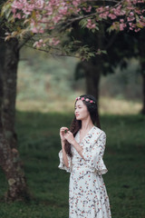 Portrait of attractive Asian teenage girl around the age of 18-25 years amid pink flower garden.