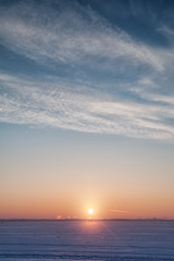 Cold winter landscape with snow, sky and sun on the horizon