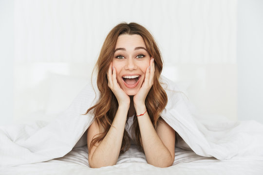 Portrait of a happy young woman lying in bed