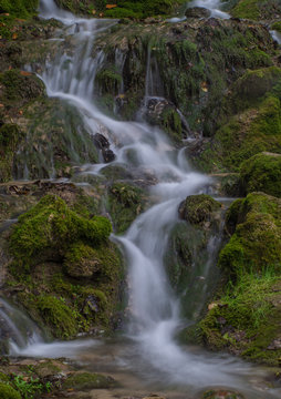 Waterfall in the forest. Green moss and stones.