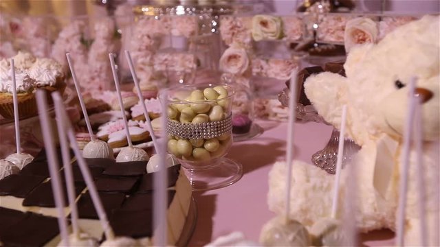 Candy bar in the restaurant, children's party, birthday, a white teddy bear with a butterfly on her neck, lit candle, teddy bear on a table Candy bar, closeup