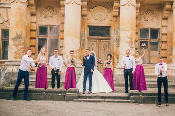 Couple of newlyweds, bride and groom together with bridesmaids and groomsmen drinking champagne outdoors hands closeup, wedding celebration with friends . 