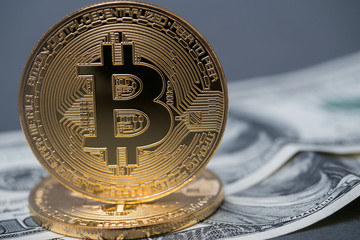 golden bitcoins on the background of 100 dollar bills