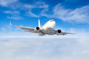 Fototapeta na wymiar White aircraft flies climbs height, flight level high in the sky above the clouds blue sky.