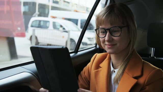 Young Businesswoman Smiling and Using a Tablet in the Car