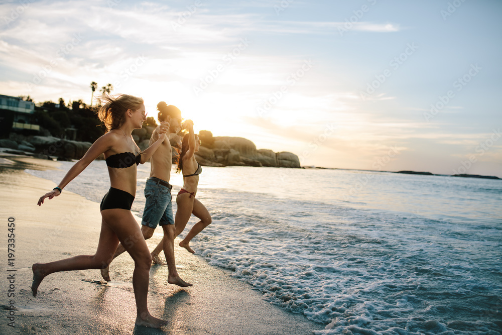 Wall mural group of happy friends running to the sea