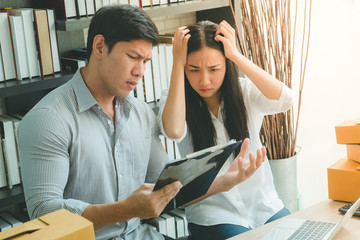 Asian couple manager sitting unhappy and stress in problem sme working at home office with workboard and box package, warm tone process style