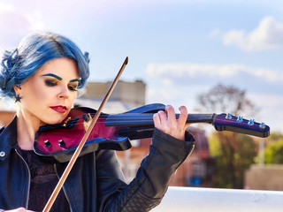 Woman perform music on violin in park outdoor. Girl performing jazz on city street. Spring outside...
