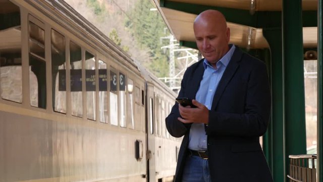Businessman Talking to Mobile and the Train Leaves from Railway Terminal Line