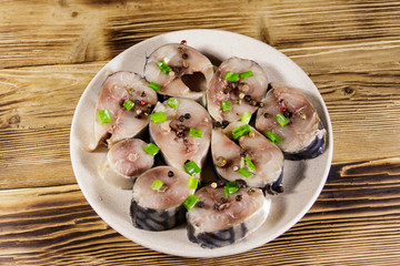 Sliced mackerel with spices on wooden table. Salted scomber on a plate