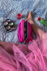 Obraz na płótnie Canvas Young teenage girl in pink skirt and sneakers on bed with cosmetics flowers, concept of fashion, lifestyle and glamor top view of flat lay with copy space