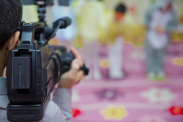 Professional Video camera operator working with his equipment, blurred background . Video camera operator working his equipment video, camera, media .Operator in kindergarden takes Novruz holiday .