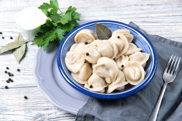 Traditional pelmeni, ravioli, dumplings filled with meat on wooden background, russian kitchen