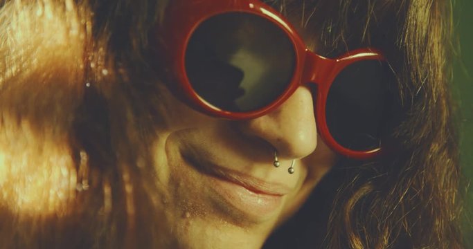 a pierced girl wearing red sunglasses while surfing on smart phone. shot in slow motion